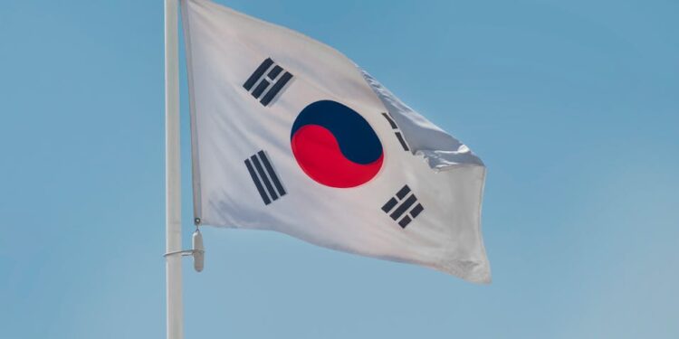 Digital currency symbols overlaid with a background of a North Korean flag and handcuffs.