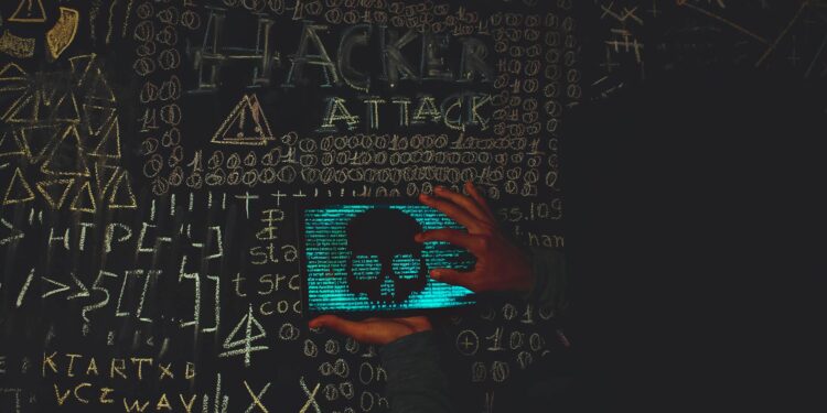 A hacker in a dark hoodie working on a computer with cryptocurrency symbols in the background.