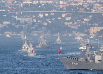 U.S. Navy ships maneuvering in the Strait of Hormuz amidst heightened tensions.