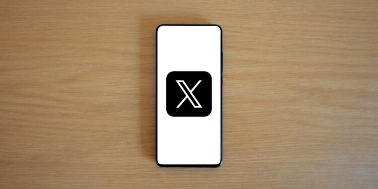 KuCoin logo displayed on a mobile screen with a Dubai skyline in the background.