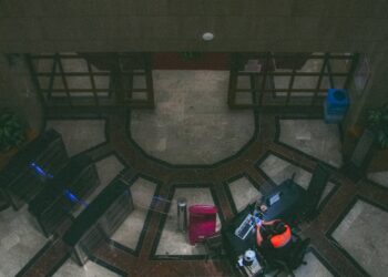 An empty bank office with security personnel monitoring outside amidst rising tensions.