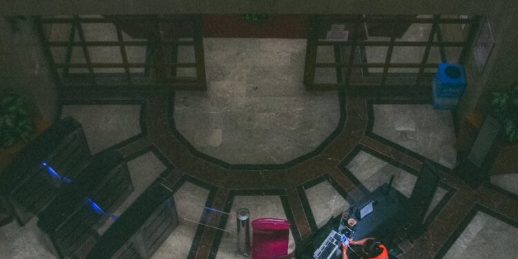 An empty bank office with security personnel monitoring outside amidst rising tensions.