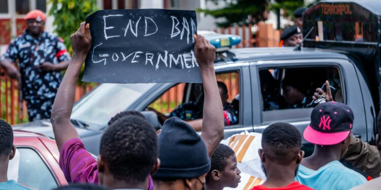 A protester holds a sign against AI military contracts outside a government building.