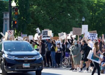 A group of individuals holding signs outside JPMorgan Chase protesting a Ponzi scheme.