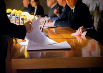Lobbyists discuss regulations at a conference table, papers and devices on display.