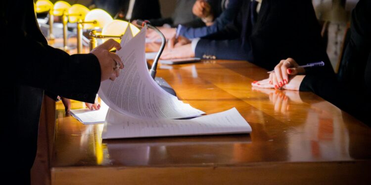 Lobbyists discuss regulations at a conference table, papers and devices on display.