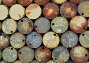 Oil market charts with a rising trend and images of oil barrels amid geopolitical conflict.