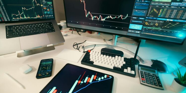 A trader monitors Bitcoin price charts on screens in a bustling finance office.