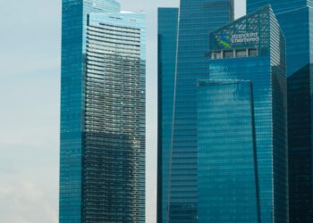 HSBC and Standard Chartered logos with cryptocurrency icons and Hong Kong skyline.