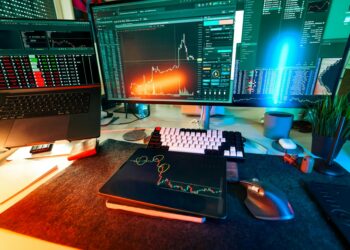 Individuals analyzing cryptocurrency transactions on multiple computer screens in an office setting.