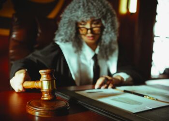 A gavel rests on a judge's bench with cryptocurrency coins in the background.