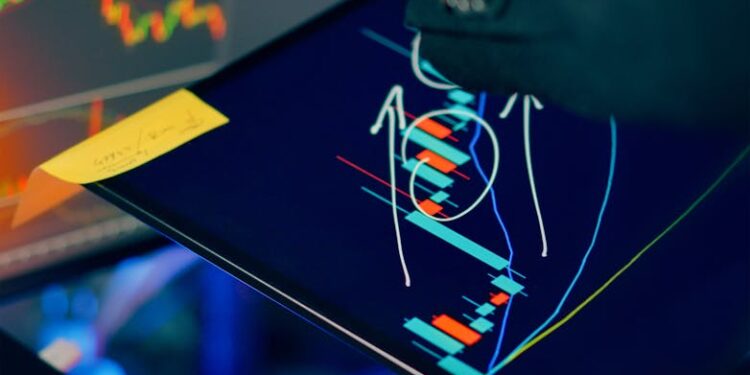 A person examines Bitcoin charts on a laptop, with financial data displayed on screens.