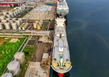 Cargo ships in a busy harbor, symbolizing oil trade and potential regulatory changes.