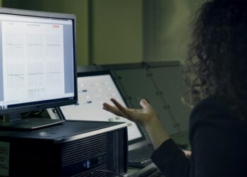 A scientist analyzes flood data on a computer screen with AI graphics in the background.