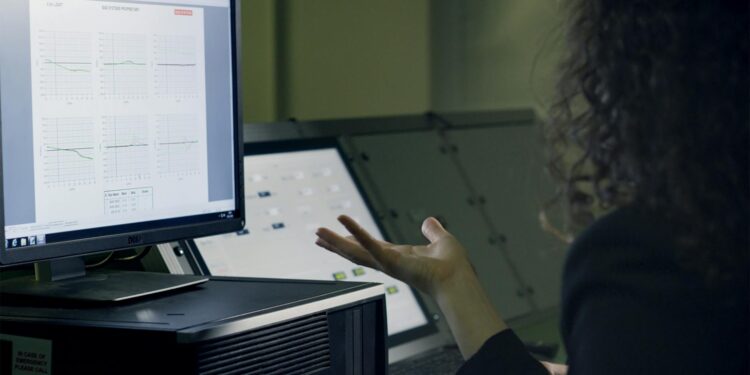 A scientist analyzes flood data on a computer screen with AI graphics in the background.