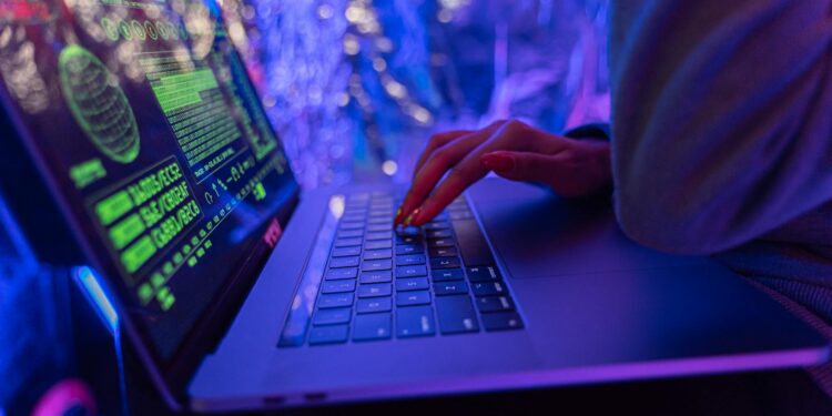 A hacker's hand on a keyboard, symbolizing cyber threats in cryptocurrency phishing attacks.