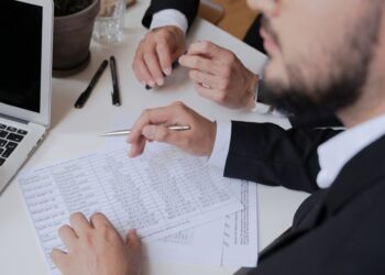 Regulatory officials discussing crypto rules at a conference table with documents and laptops.