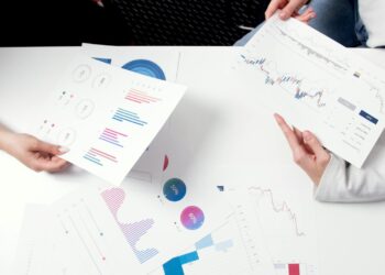 Business professionals discussing financial documents with charts and graphs on a table.