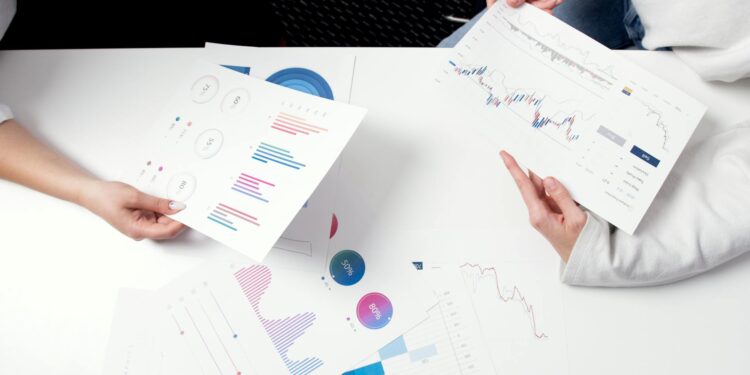 Business professionals discussing financial documents with charts and graphs on a table.