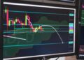 A digital chart showing Bitcoin's price drop below $69,200 with financial graphs in the background.