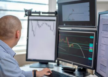 Traders monitor financial charts on multiple screens with S&P 500 logos in a digital trading hub.