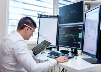 Traders monitoring oil futures on electronic screens in a busy financial trading environment.