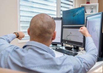 Team celebrating in an office, surrounded by screens displaying crypto market data and charts.