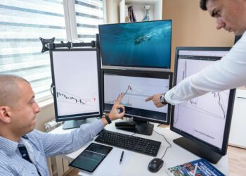 Traders analyzing crypto market trends on multiple screens in a bustling finance office.