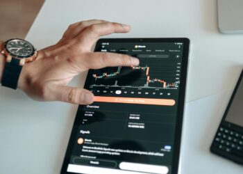 Investor reviewing Bitcoin graphs on a digital screen with financial charts in a Japanese setting.