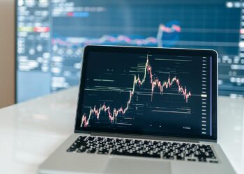 A trader viewing cryptocurrency charts on a computer screen in a financial office.