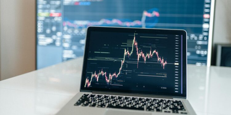 A trader viewing cryptocurrency charts on a computer screen in a financial office.