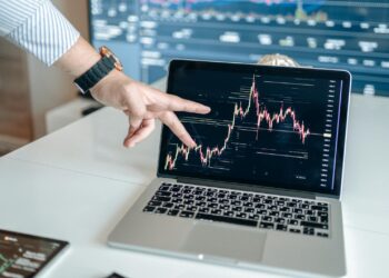 A financial advisor examines a Bitcoin chart on a digital tablet in an office setting.