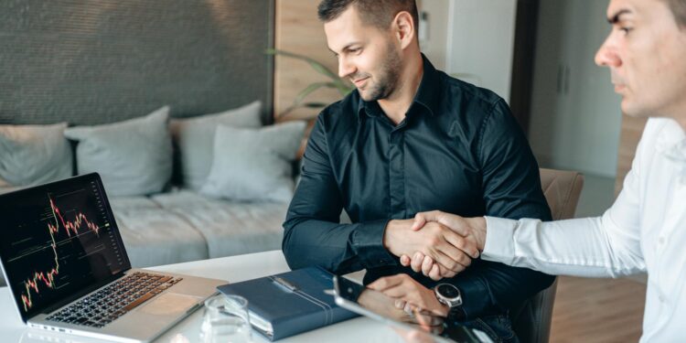 Investment handshake between two business professionals with digital stock graphs in the background.