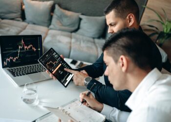 Two professionals discussing blockchain technology with digital charts and graphs in the background.