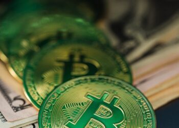 Stack of dollar bills next to a digital crypto coin, symbolizing financial fraud.