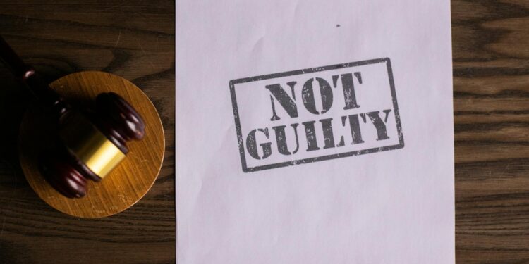 Sam Bankman-Fried in court, surrounded by legal documents and media reporters.