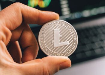 A close-up of a digital currency symbol overlaying a blurred financial market background.