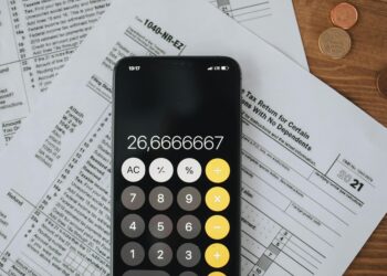 Revolut logo displayed on a smartphone beside financial documents and a calculator.