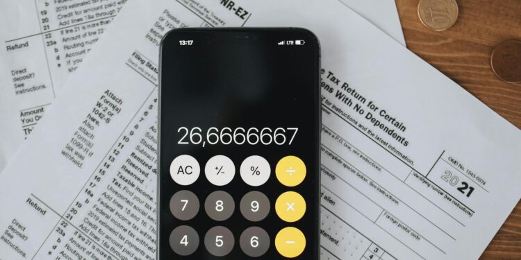 Revolut logo displayed on a smartphone beside financial documents and a calculator.