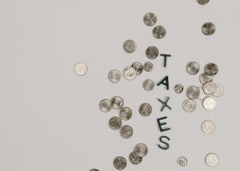 Graphic showing cryptocurrency coins with a tax symbol overlay, highlighting new regulations.