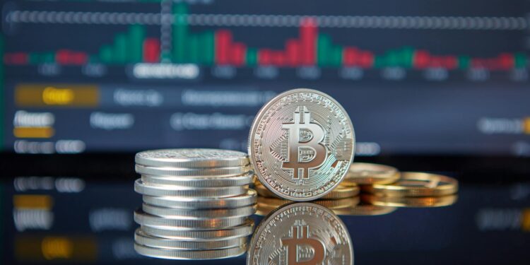 Bitcoin coins stacked with a fluctuating stock market graph in the background.