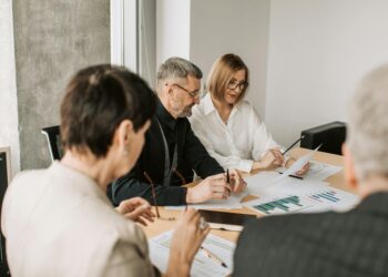 Business professionals discussing financial strategy with documents and graphs on a table.