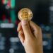 A lawyer holds a gavel with digital currency symbols in the background, representing finance and crypto.