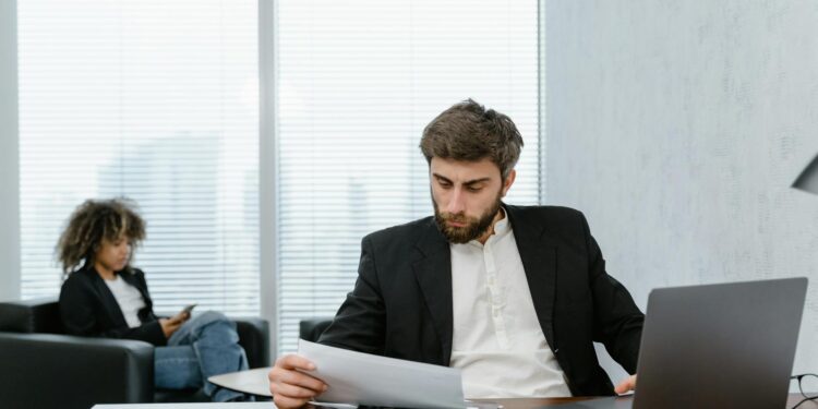 Employees in a corporate office reviewing job loss reports in the crypto industry.