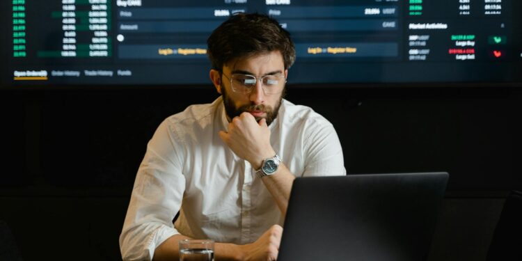 A developer analyzing blockchain data on a laptop with cryptocurrency graphics in the background.