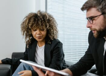 Two business professionals discuss blockchain technology over a laptop, showcasing crypto finance innovation.