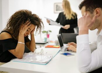 Employees in an office looking concerned as news of AI-related layoffs circulates.