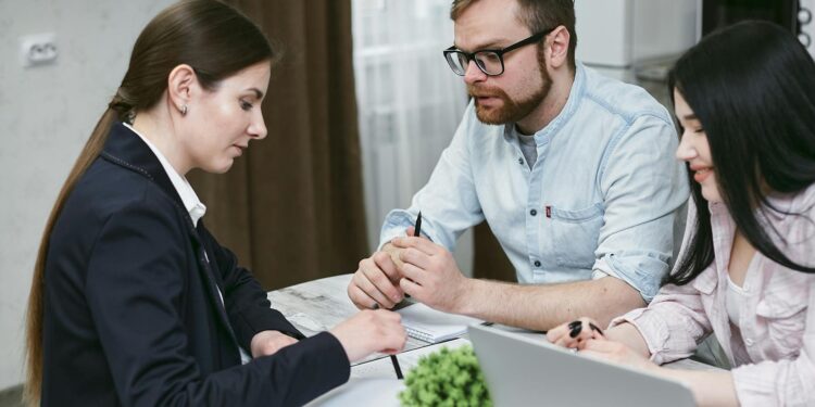 Two businesspeople discuss financial documents with cryptocurrency symbols in the background.
