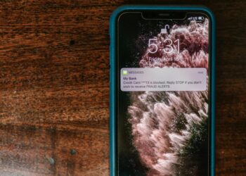 A smartphone displaying cryptocurrency icons with a warning alert on the screen.