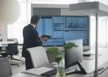 A financial analyst examines Bitcoin charts and ETF data in a modern office setting.